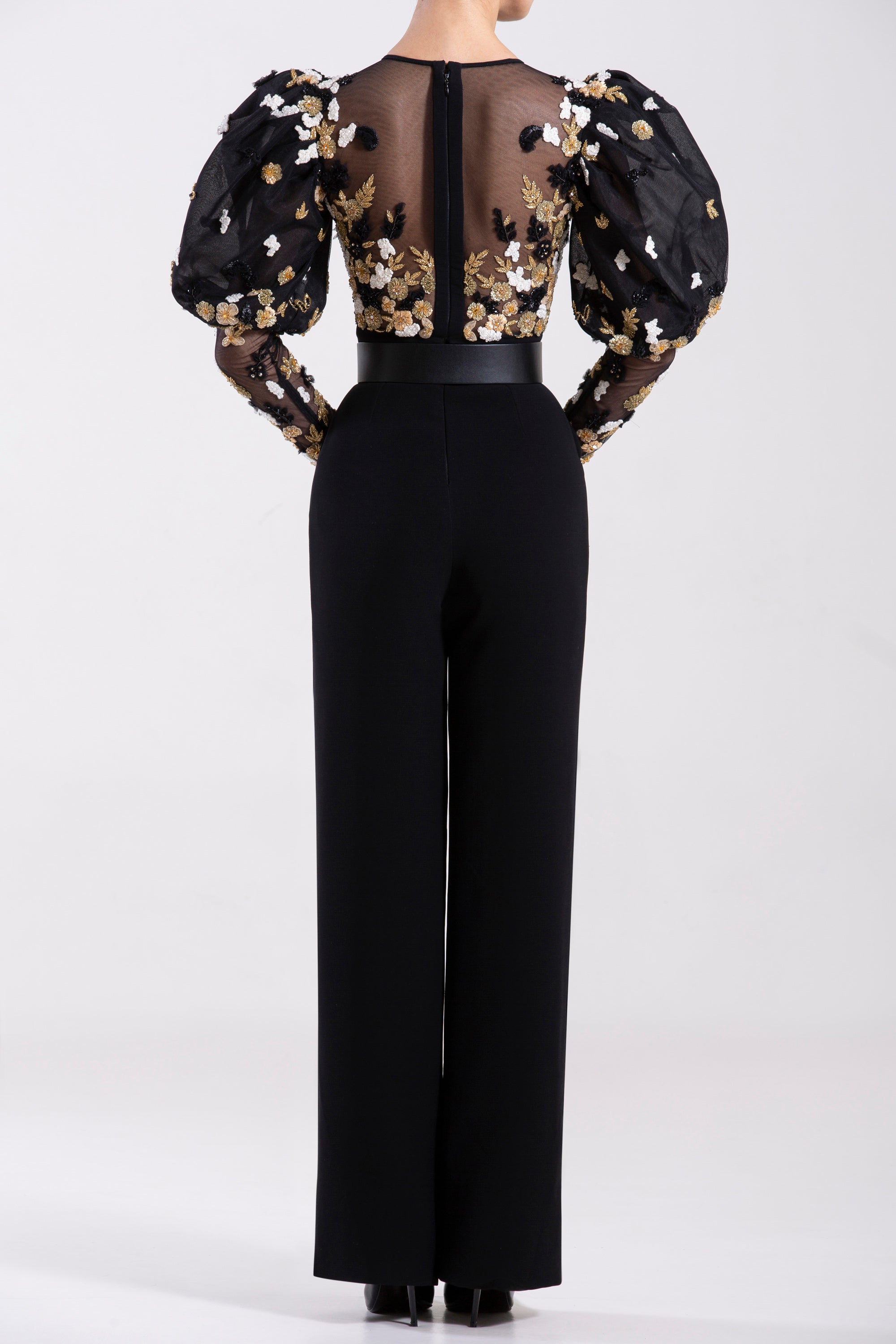 Crepe marocain jumpsuit with a tulle beaded top and sleeves, paired with a  signature black leather belt.